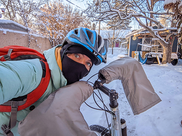 Woman in winter biking gear shows off the handle-bar mitts she made.