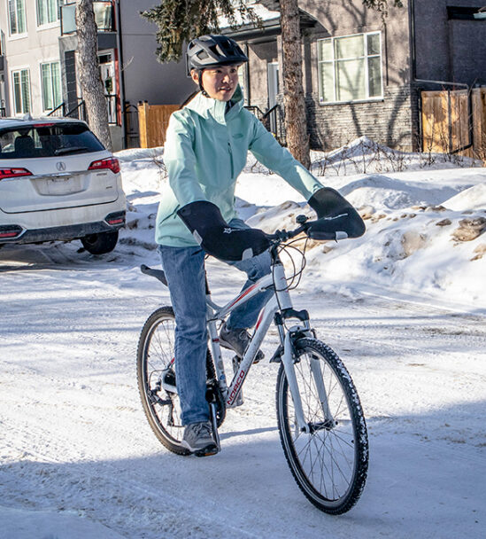 Yuxuan Hou rides her bike along a snowy street,